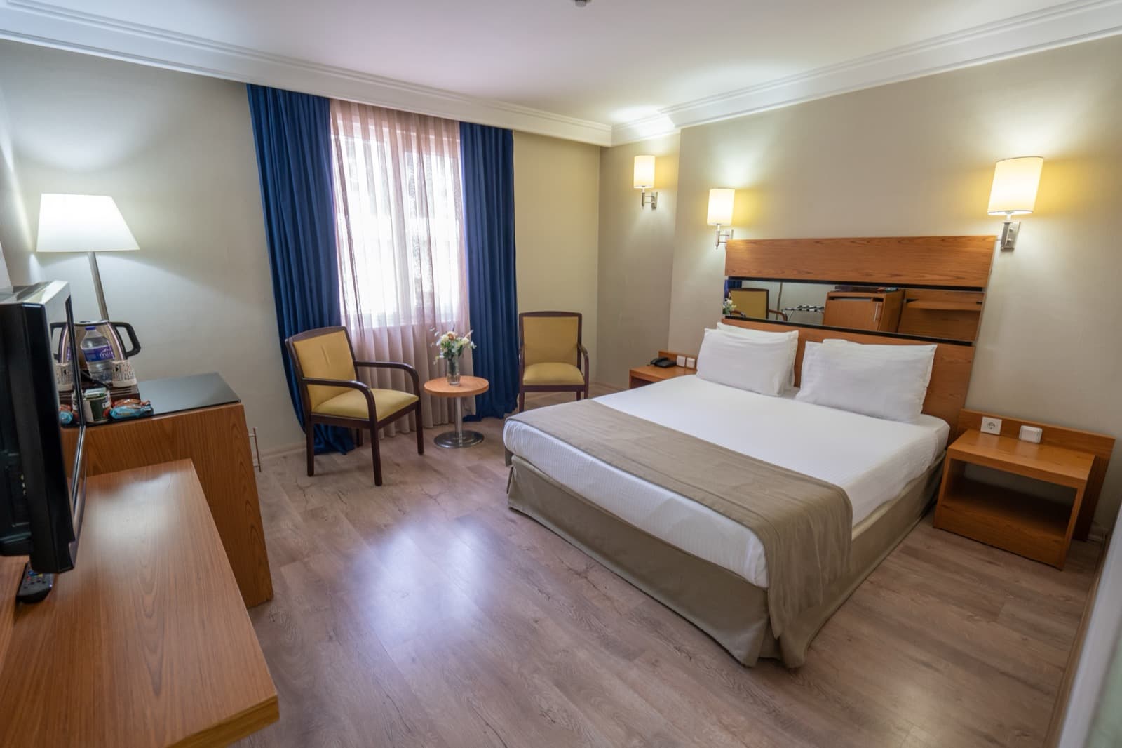 Standard double room with wooden headboard, armchairs and city-facing window at The Green Park Hotel Taksim