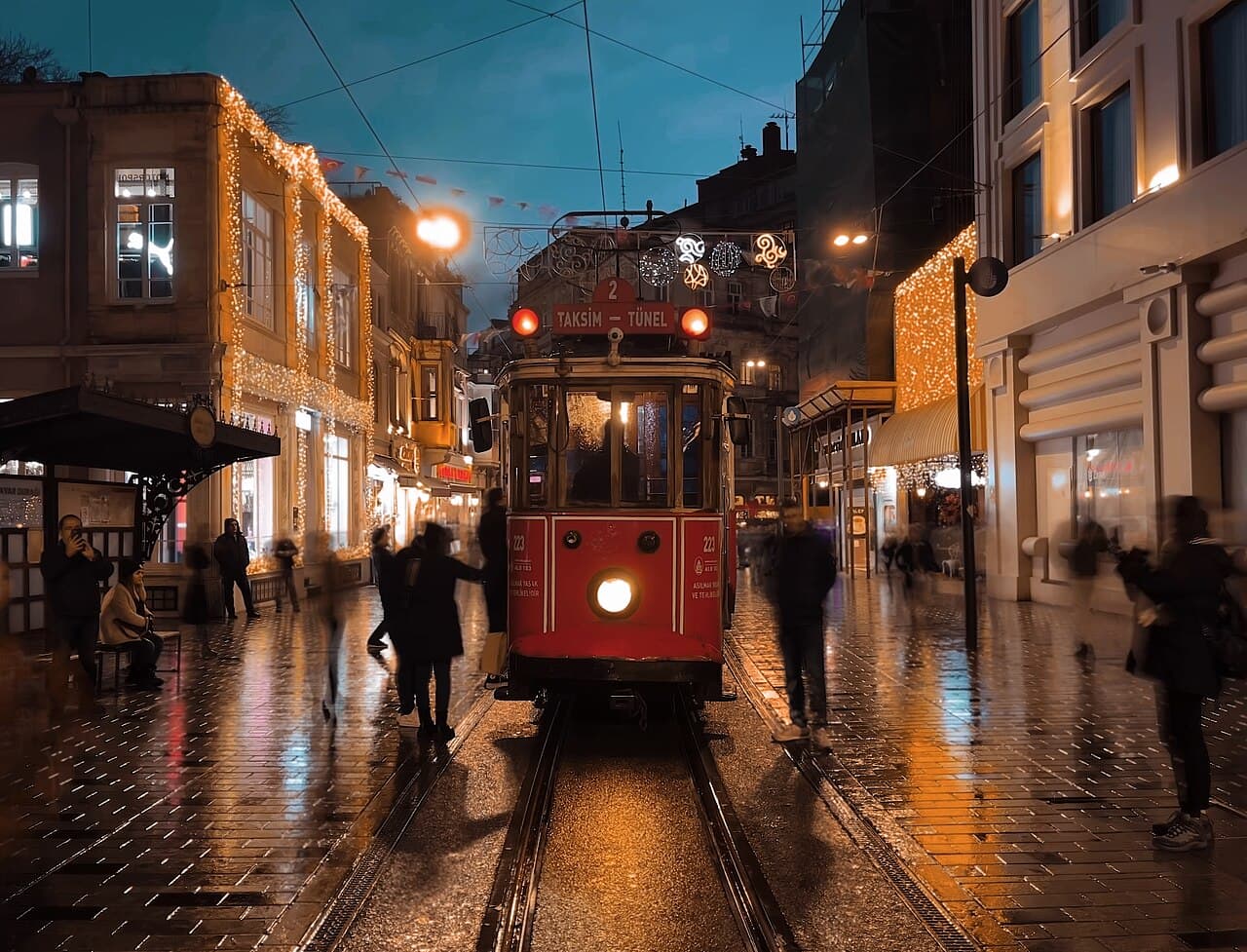 Red T2 nostalgic tram on Istiklal Street at night under festive lights